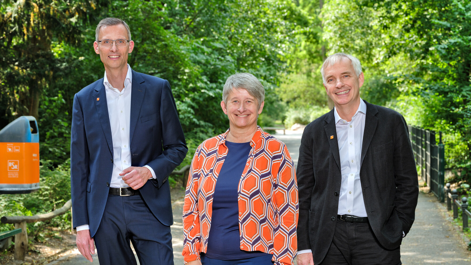 Die Vorsitzende des BSR-Vorstands Stephanie Otto, der Vorstand für Finanzen und Digitalisierung Dr. Christoph Vielhaber und der Vorstand Personal und interne Dienstleistungen stehen in einem grünen Park.