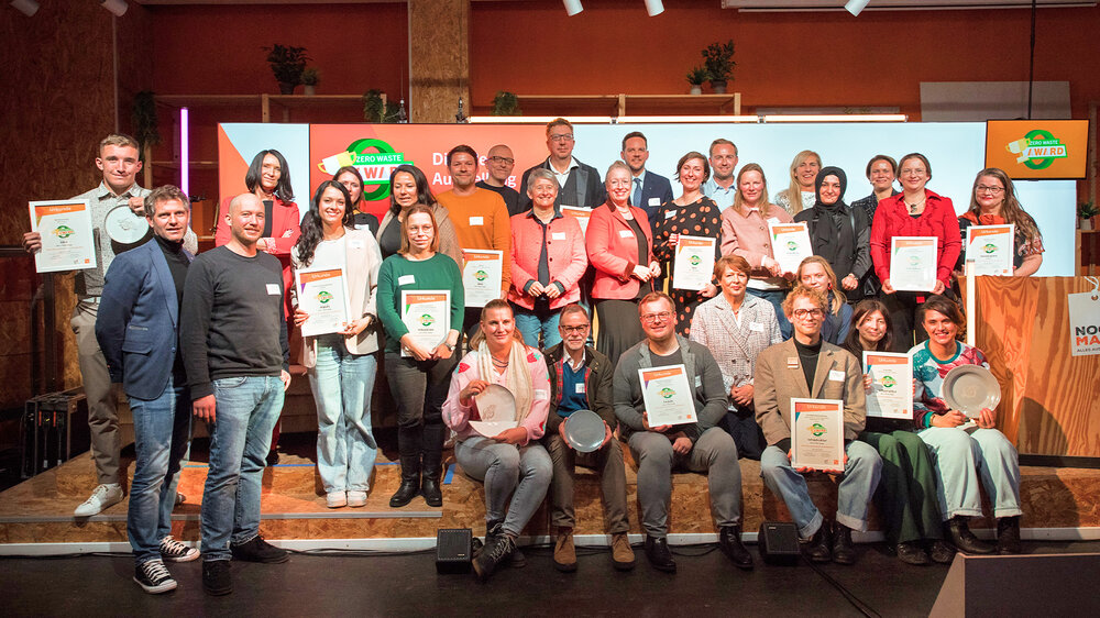Preisträger:innen und Beteiligte des Zero Waste Award stehen gemeinsam auf der Bühne mit ihren Auszeichnungen