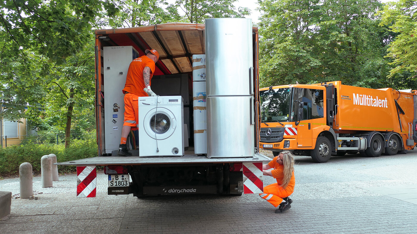 BSR-Mitarbeitende verladen Elektrogeräte wie Waschmaschine und Kühlschrank auf einen Lkw