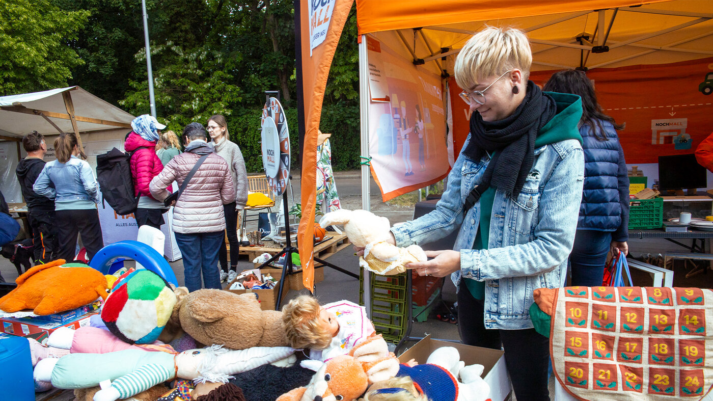 Besucherin nimmt gut erhaltene Gegenstände an einem Kieztag-Stand der BSR mit