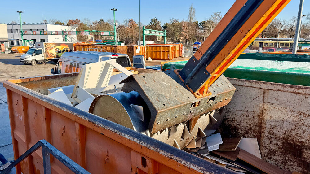 Auf einem Recyclinghof verdichtet eine Presse Sperrmüll in einem großen Container 
