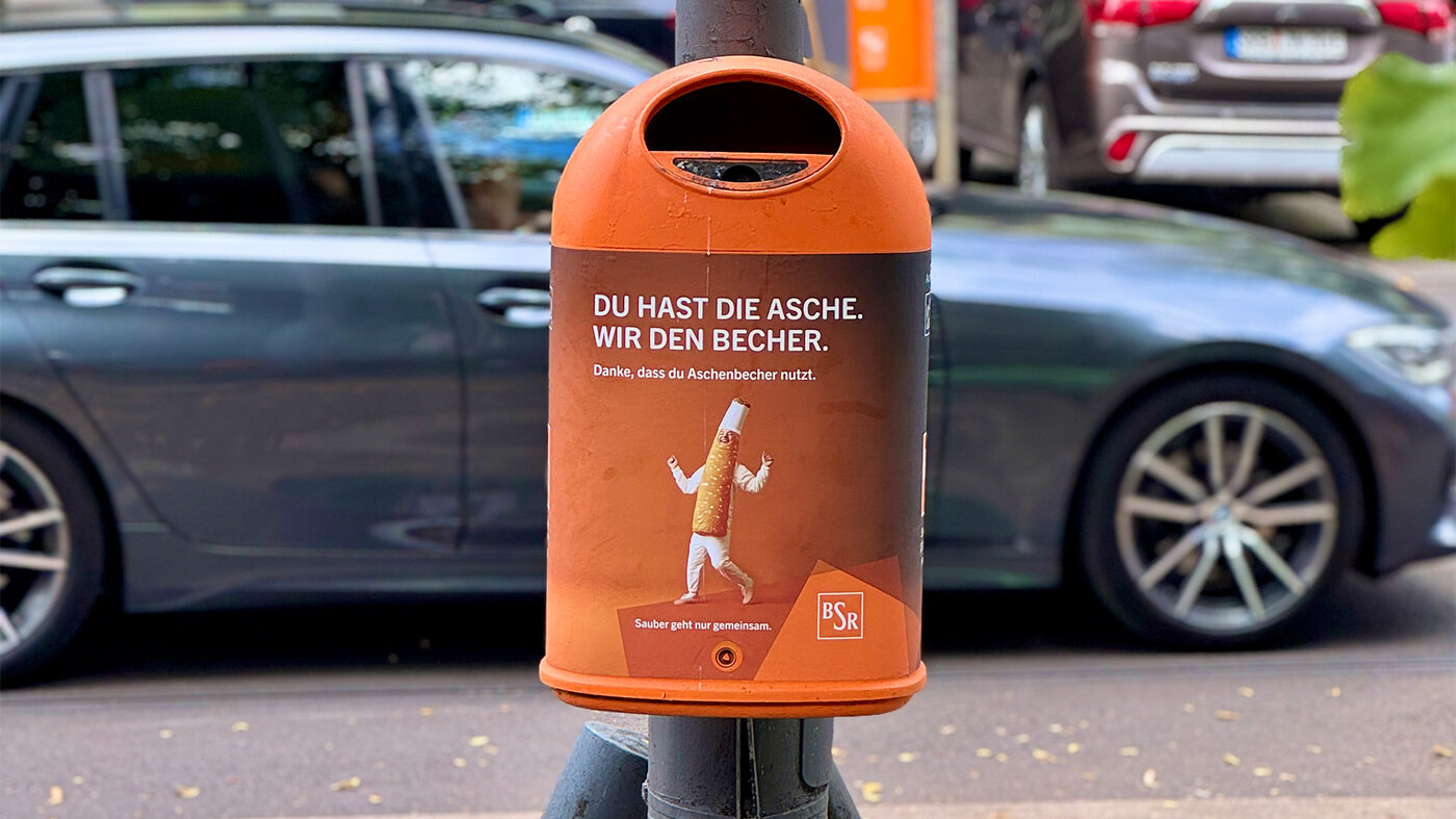 Papierkorb mit dem Kampagnenslogan „Du hast die Asche. Wir den Becher.“ zur richtigen Entsorgung von Zigarettenkippen
