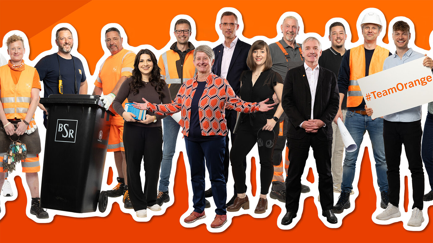 Vielfältiges BSR-Team mit Mülltonne, Arbeitskleidung und Schild „#TeamOrange“ 