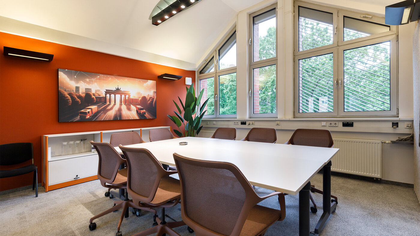 Neu gestalteter Besprechungsraum mit großem Tisch, flexiblen Sitzplätzen und heller Fensterfront