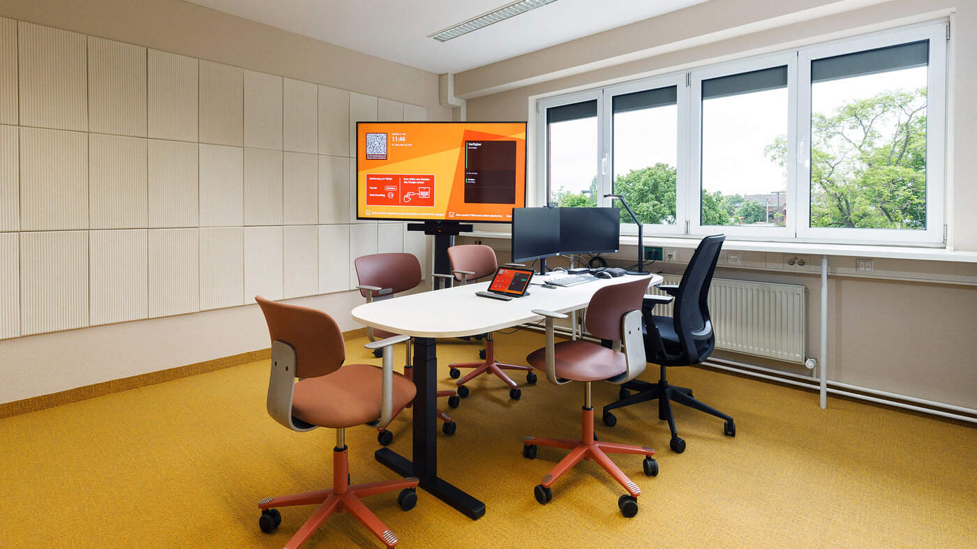 Kompakter Teamraum mit variablen Sitzplätzen und digitaler Ausstattung für gemeinsames Arbeiten