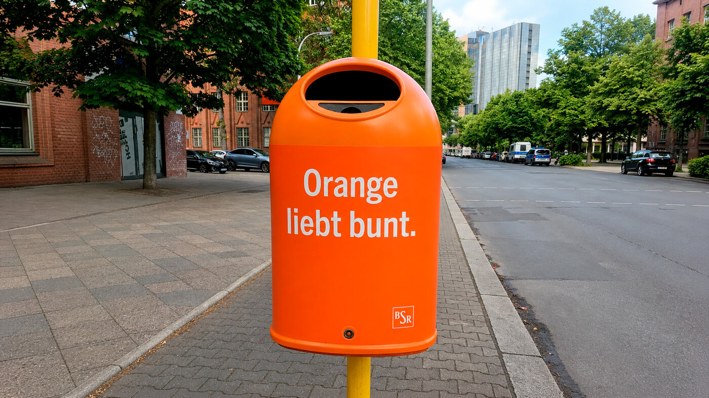 Orangefarbener BSR-Papierkorb mit der Aufschrift „Orange liebt bunt.“ im Berliner Straßenraum