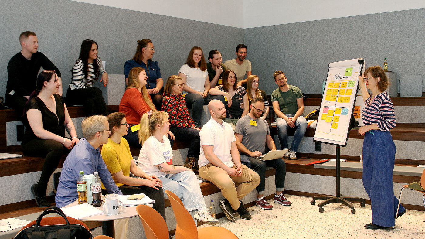 Workshop der BSR mit Teilnehmenden auf Sitzstufen und einer Moderatorin am Flipchart